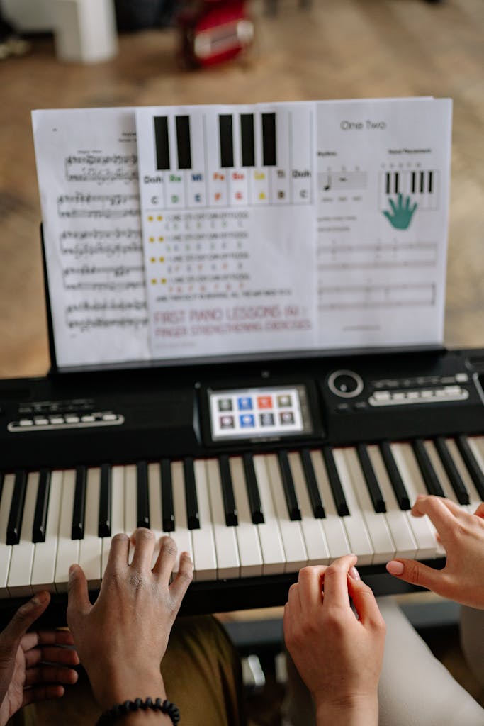 Close-up view of hands playing piano with sheet music, learning session.