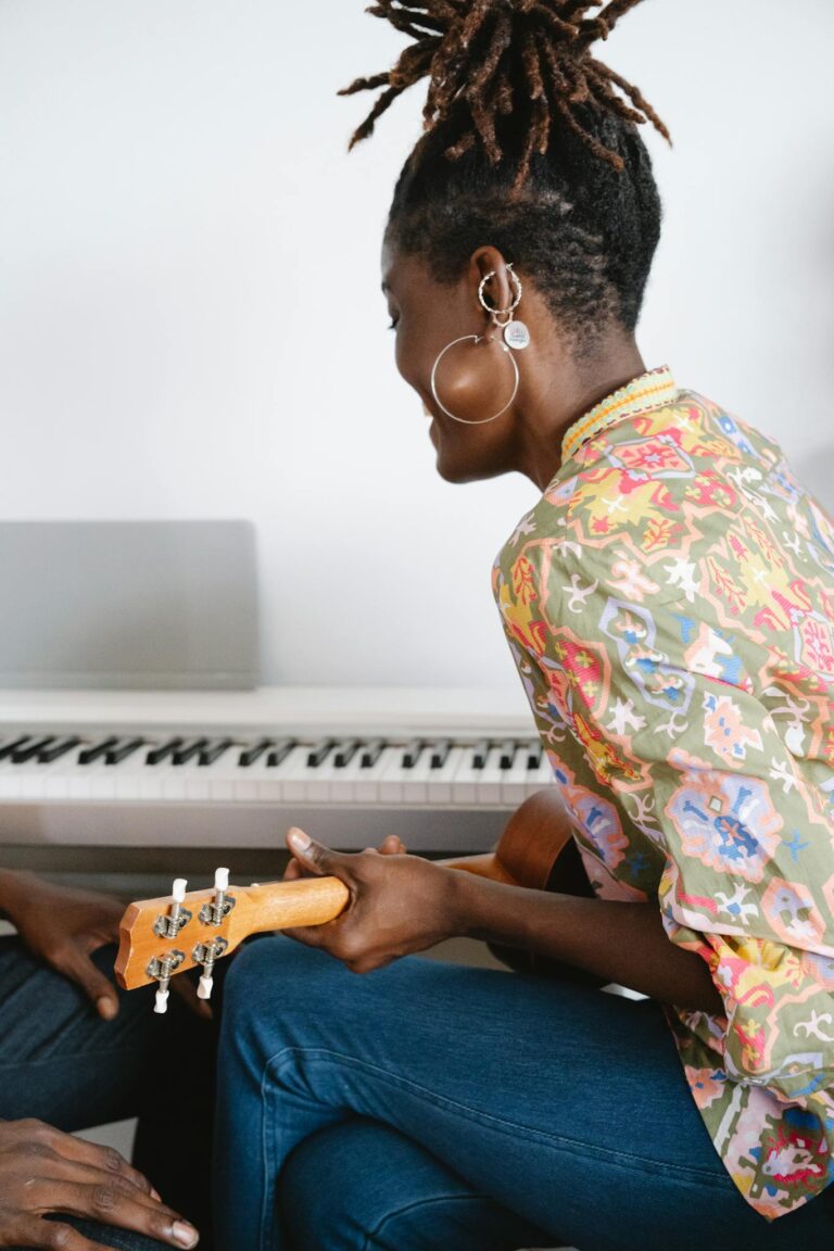 African American woman playing a ukulele with a keyboard piano in the background, creating a musical and artistic vibe.