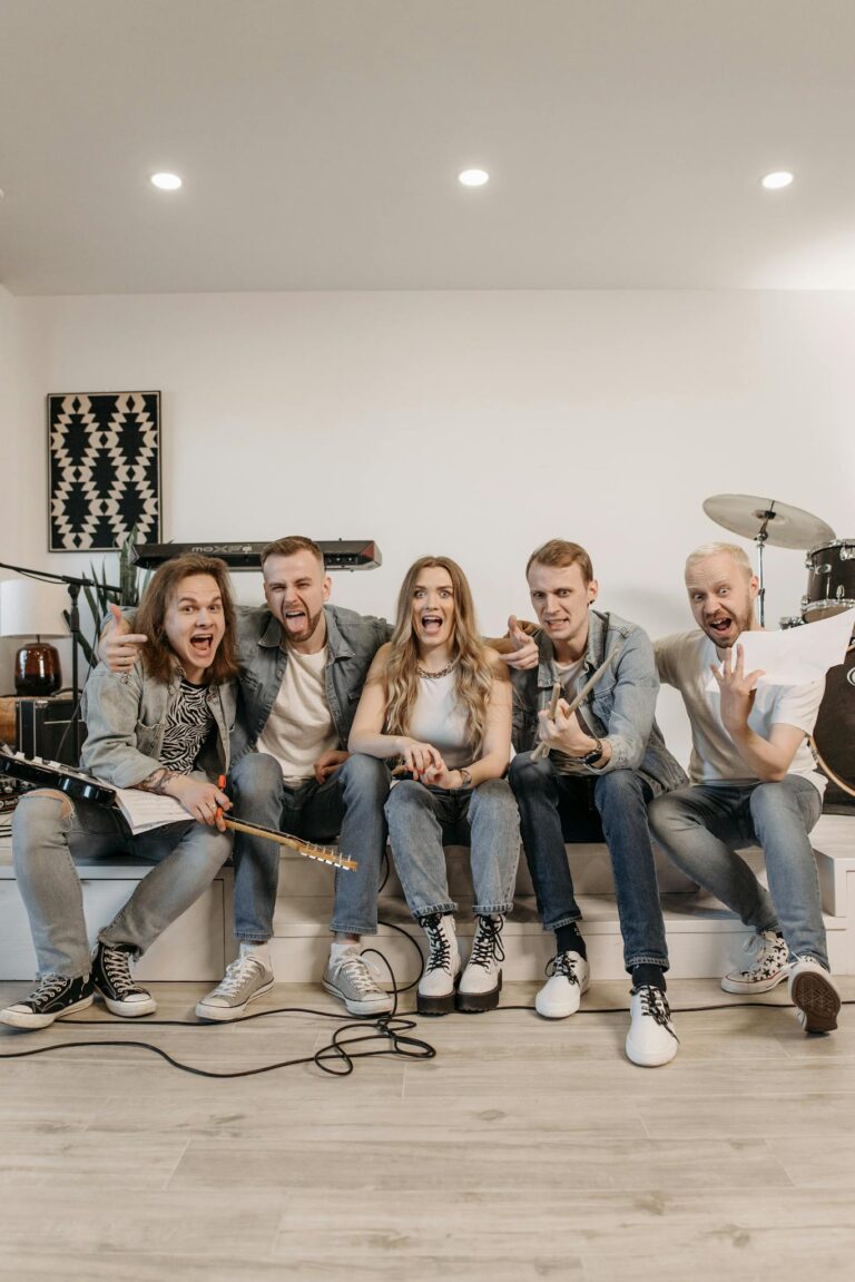 Lively band posing indoors with instruments, showcasing unity and enthusiasm.